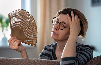 Middle aged woman fanning her face to cool off.